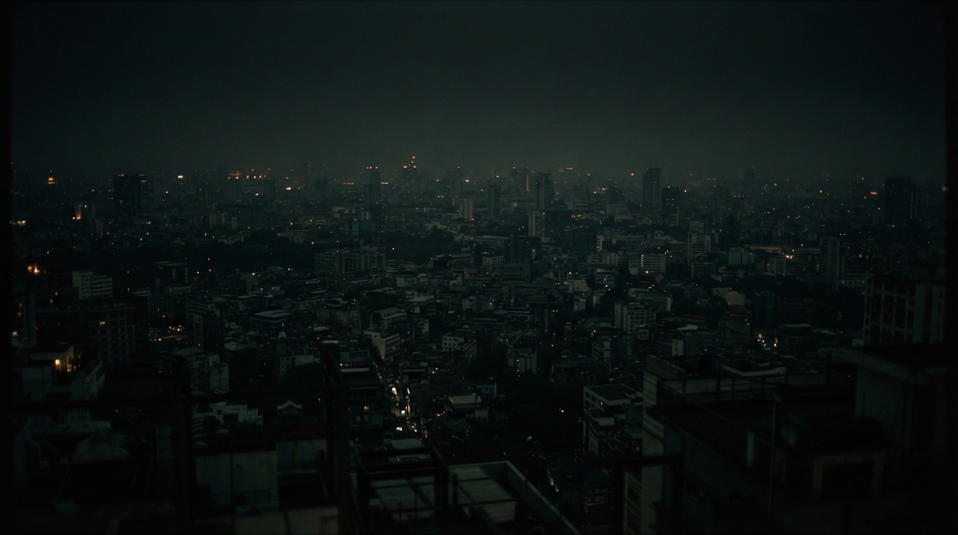 Hazy nighttime cityscape viewed from above, with dense buildings and scattered lights.